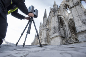 Un technicien utilise un scanner laser 3D sur trépied pour numériser l'architecture d'une cathédrale gothique ancienne.